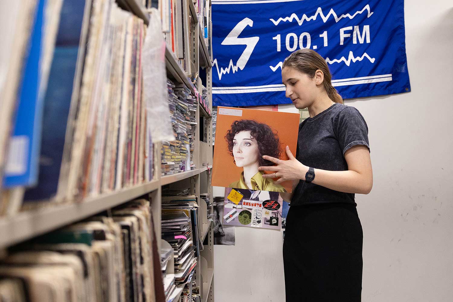 A student browses a shelf of records and CDs.
