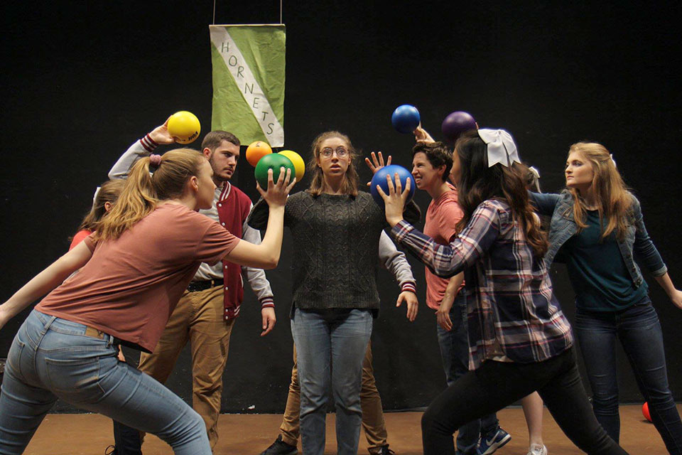 Performers on stage holding colorful balls