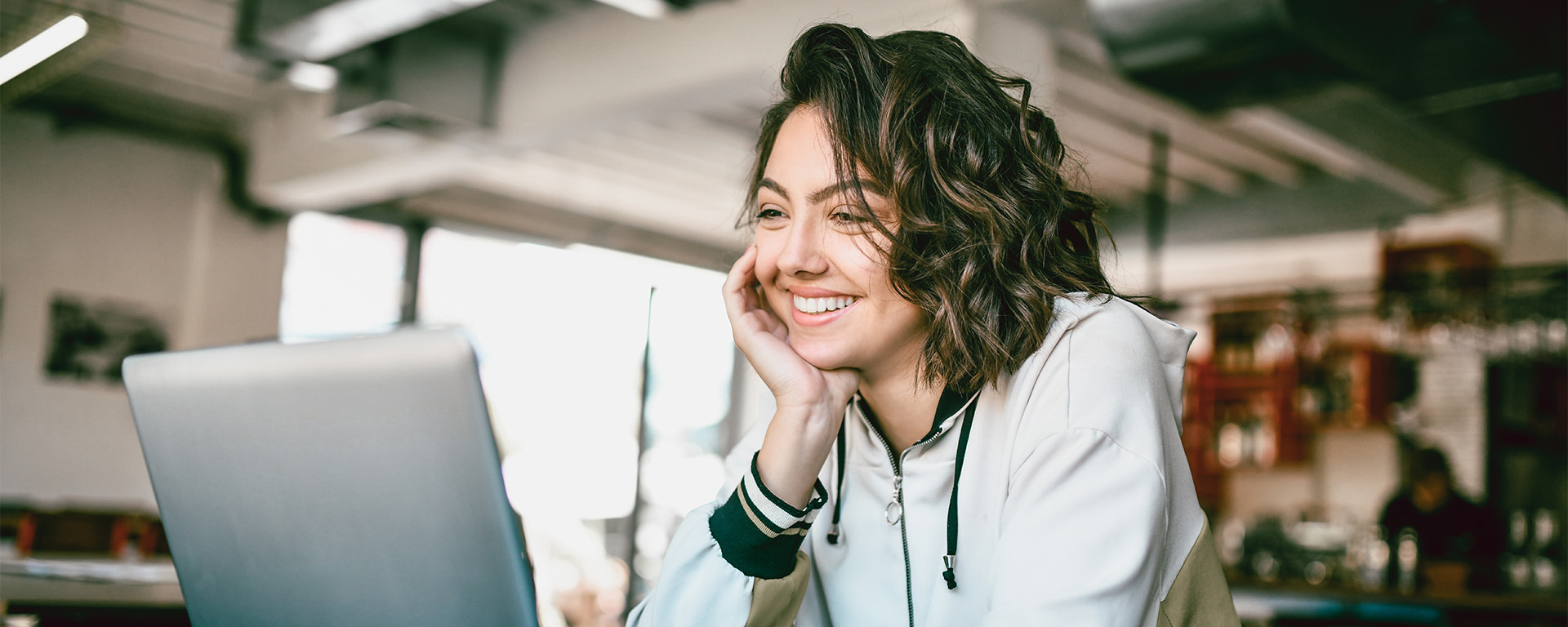 A person smiles while looking at a laptop