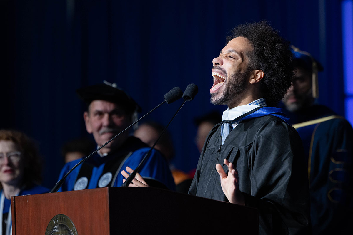 A person sings the National Anthem from the podium during Commencement.