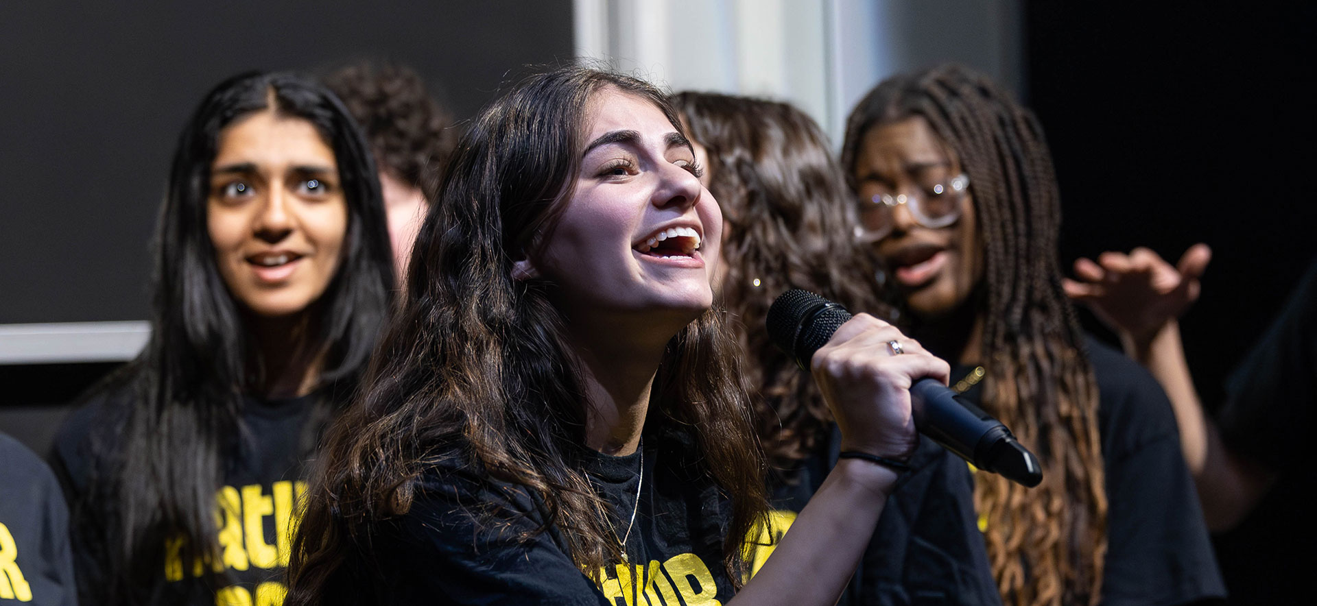 A group of students sing a cappella on stage.