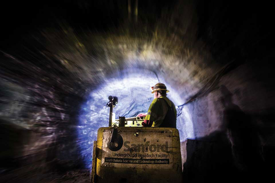 A person in a hard hat working with machinery in a tunnel